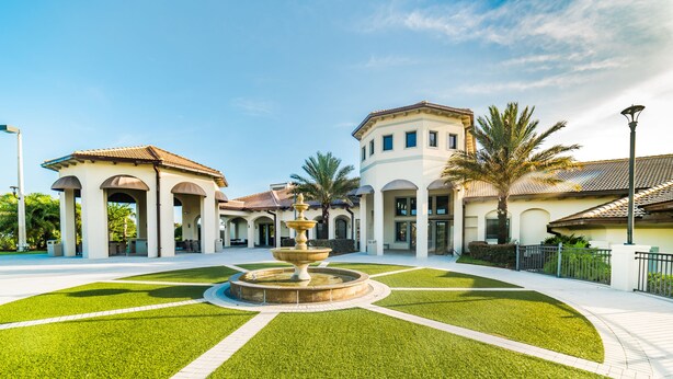 A courtyard with a fountain, palm trees, and a building with arched walkways. - Aco240235 - Champions Gate Resort - 6 Bed 6 Baths Hotel (Davenport)