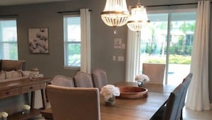 A dining area with a wooden table, six chairs, and two hanging chandeliers. - Aco258800 - The Encore Club Resort - 8 Bed 6.5 Baths Villa (Kissimmee)