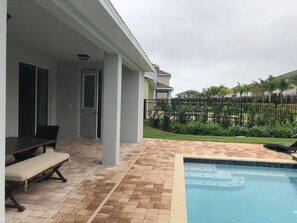 Ein überdachter Patio-Bereich mit Pool, Esstisch und Bank.