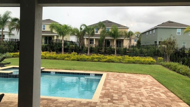 A swimming pool with a tiled deck, surrounded by a well-maintained lawn and a fence. - Aco258800 - The Encore Club Resort - 8 Bed 6.5 Baths Villa (Kissimmee)