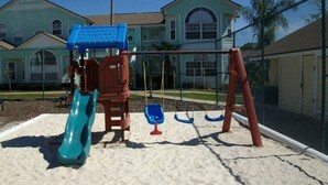 Un parque infantil con tobogán, columpios y una estructura para escalar.