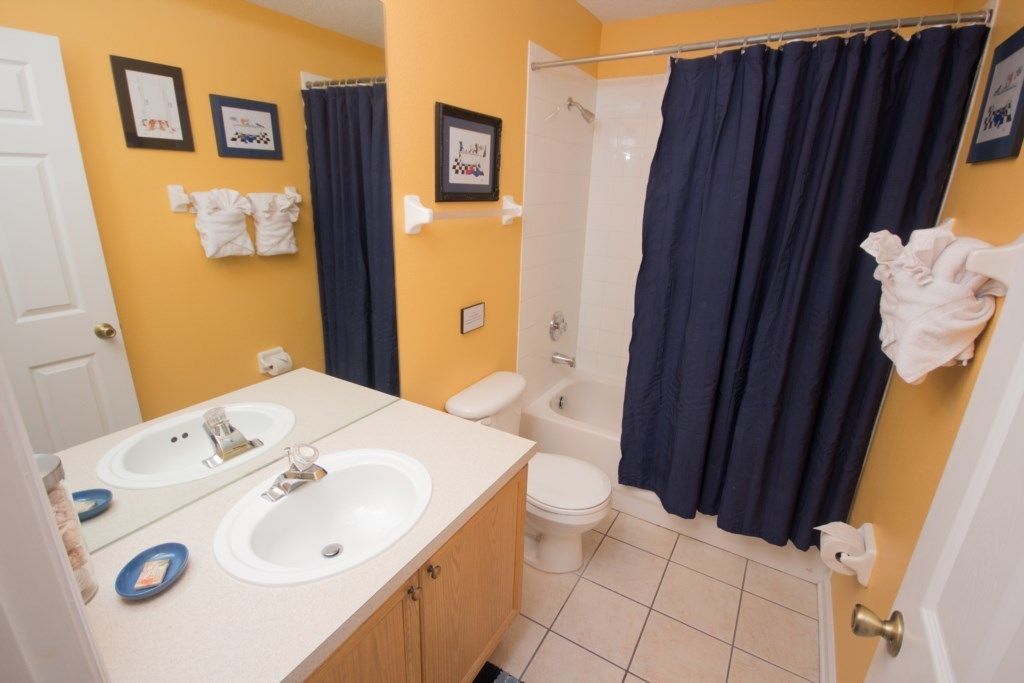 Une salle de bain avec deux lavabos, des toilettes, une baignoire et un rideau de douche.