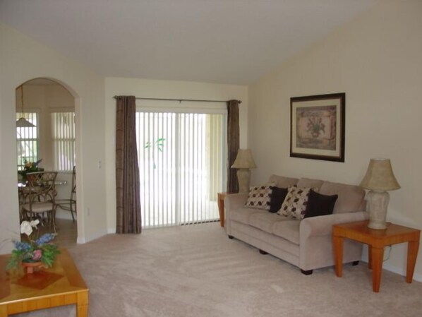 A living room with a beige sofa, two lamps, a wooden side table, and a framed picture on the wall.