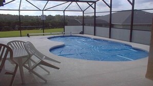 Une piscine intérieure au design incurvé, entourée d’un espace abrité où se trouvent des chaises.