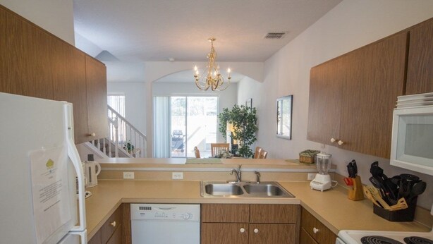 A modern kitchen with wooden cabinets, a dishwasher, a stove, and a sink.