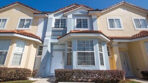 A two-story residential building with a symmetrical facade, a central balcony, and a small porch area.