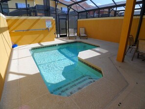 An indoor swimming pool with clear water, surrounded by yellow walls and a glass ceiling.