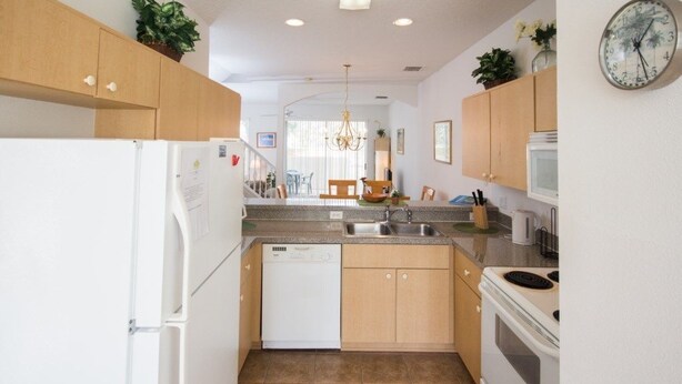 A compact kitchen with wooden cabinets, a dishwasher, a stove, and a microwave. - Ip60350 - Fiesta Key - 3 Bed 2.5 Baths Townhome (Kissimmee)