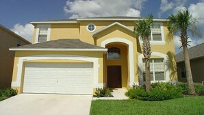 A two-story house with a garage, a front door, and a small porch. - Ahr112 - Emerald Island - 7 Bed 4 Baths Villa (Kissimmee)
