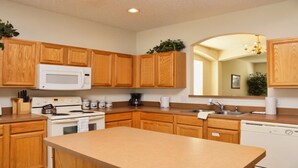 A kitchen with wooden cabinets, a microwave, stove, sink, and a dishwasher. - Ahr112 - Emerald Island - 7 Bed 4 Baths Villa (Kissimmee)