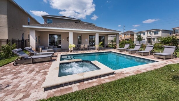 Una propiedad residencial con piscina, mobiliario de exterior y césped bien cuidado.