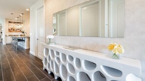 Una cocina moderna con piso de madera oscura, una encimera blanca y un espejo grande colgando sobre ella.