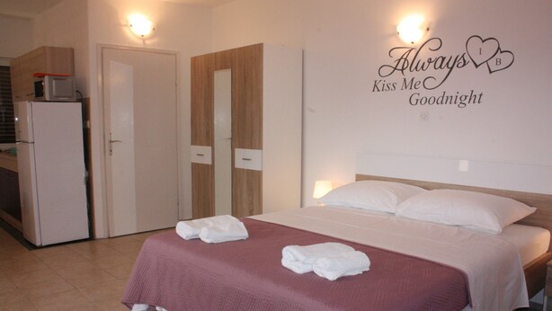 A hotel room with a bed, a wardrobe, and a kitchenette. - Apartments Blato-M (Pag)
