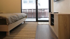 A bedroom with a bed, a TV mounted on the wall, and a sliding glass door leading to a balcony. - Aunny House (Bangkok)