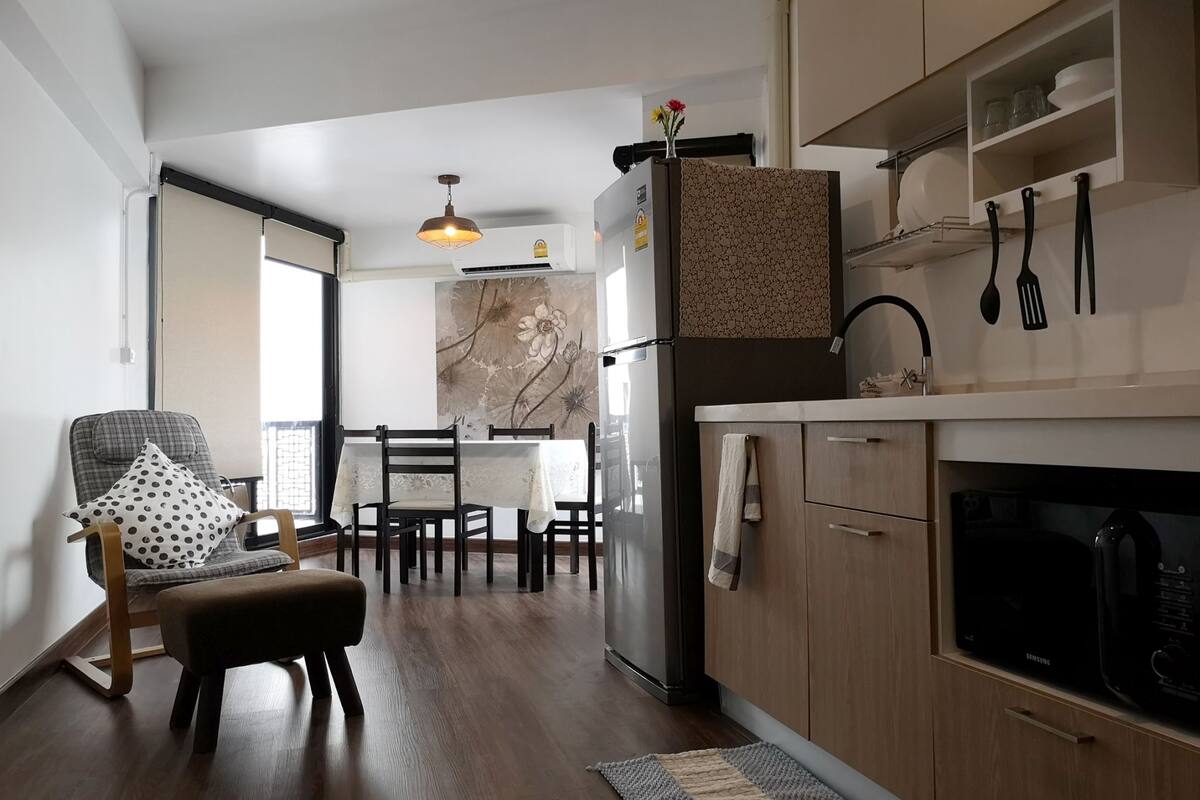 A modern kitchen with wooden cabinets, a dining area with a table and chairs, and a large window providing natural light.