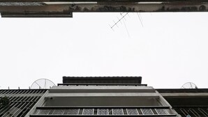 A multi-story building with a flat roof, visible ventilation grills, and a central light fixture. - Aunny House (Bangkok)