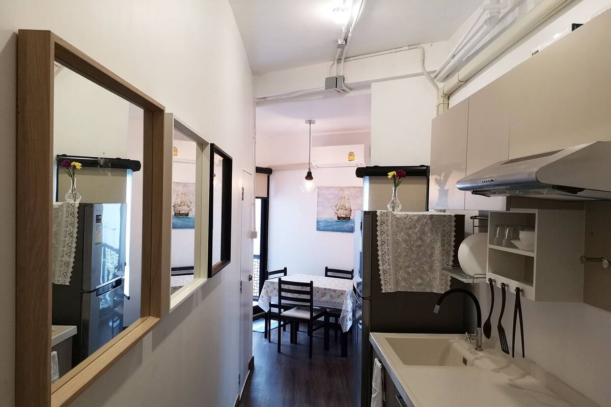 A compact kitchen with a dining area, featuring a refrigerator, sink, and cabinets.