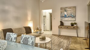 A living room with a sofa, a coffee table, a chandelier, a painting, and a TV. - Baratero City II Apartment (Sofia)