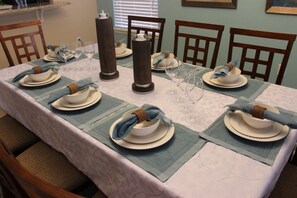 Une table à manger dressée avec des assiettes, des verres et des serviettes.