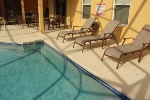 Un espace piscine avec des chaises longues et un panneau indiquant « Il est interdit de plonger ».