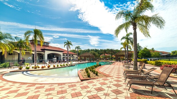 A pool area with lounge chairs and palm trees.