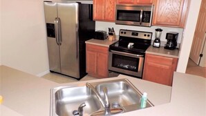 A compact kitchen with stainless steel appliances, wooden cabinets, and a built-in oven.