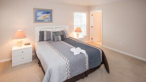 Un dormitorio ordenado con cama, mesitas de noche y ventana.