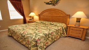 A bedroom with a floral bedspread, wooden headboard, two bedside tables with lamps, and a nightstand with a decorative item. - Tr112 - Terrace Ridge - 2 Bed 2 Baths Condo (Davenport)