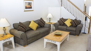 A living room with two grey sofas, a wooden coffee table, and a staircase.