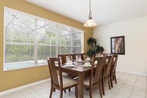 A dining area with a large window, a hanging light fixture, and a potted plant. - Aco243016 - Bella Vida Resort - 6 Bed 5.5 Baths Villa (Kissimmee)