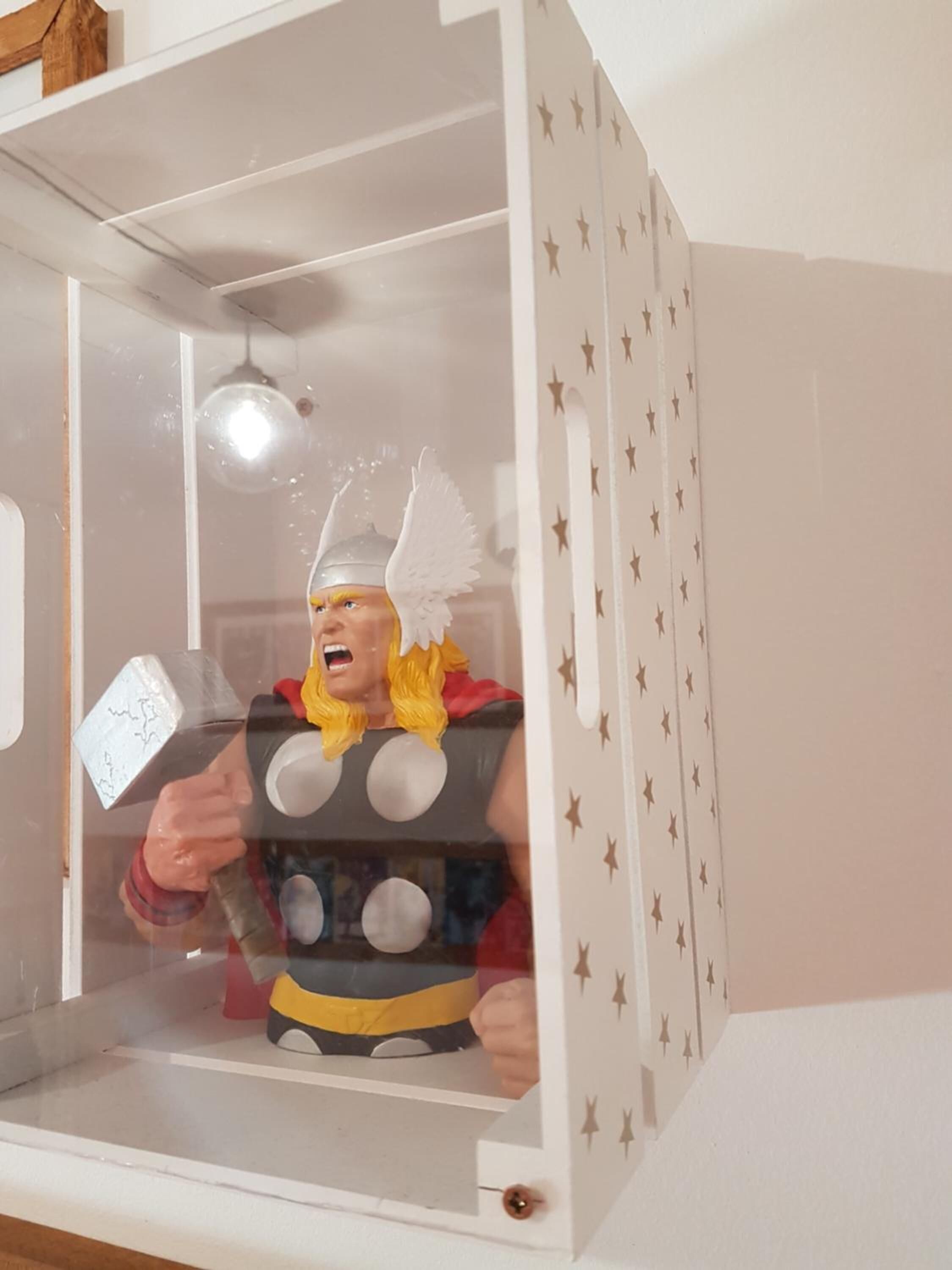 A toy Thor figure in a display case with a star pattern on the walls.