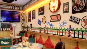 A bar with a variety of liquor bottles, a television, and several framed signs on the wall. - Barri Antic Hostel & Pub (Andorra la Vella)