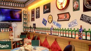A bar area with a variety of liquor bottles, a television, and memorabilia on the wall. - Barri Antic Hostel & Pub (Andorra la Vella)