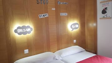 A bedroom with a wooden headboard, two pillows, and motivational stickers on the wall.