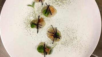 A white plate with four food items, each garnished with a green leaf and a black garnish, on a textured surface.