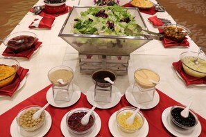 A buffet table with various food items and serving utensils. - QueenSir International Hotel (Xi'an)