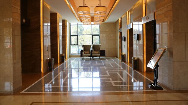 A spacious lobby with a polished floor, two seating areas, and a reception desk. - QueenSir International Hotel (Xi'an)