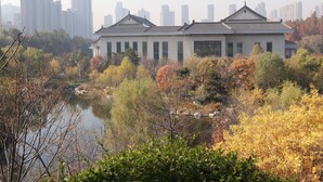 A traditional building with a symmetrical facade, surrounded by autumn foliage and a body of water. - QueenSir International Hotel (Xi'an)