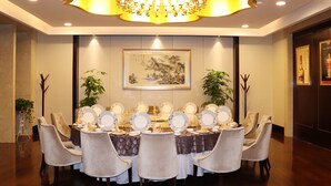 A formal dining room with a chandelier, round tables, and chairs. - QueenSir International Hotel (Xi'an)
