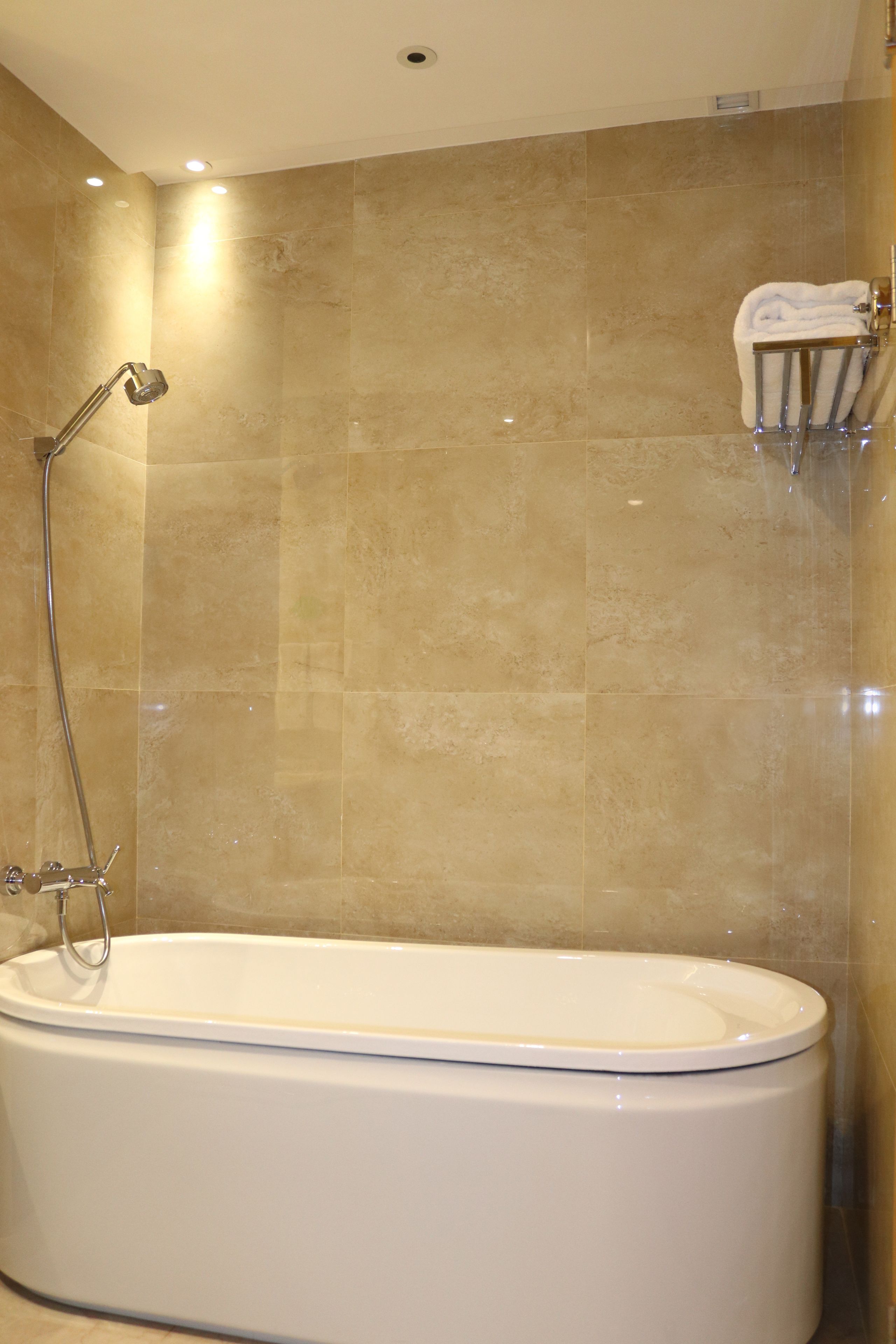 A modern bathroom with a freestanding bathtub, a showerhead, and a towel rack.