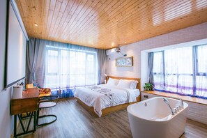A modern bedroom with a wooden ceiling, a large bed, a bathtub, and a desk with a chair. - Maan Coco Travelling Boutique Inn (Shenzhen)