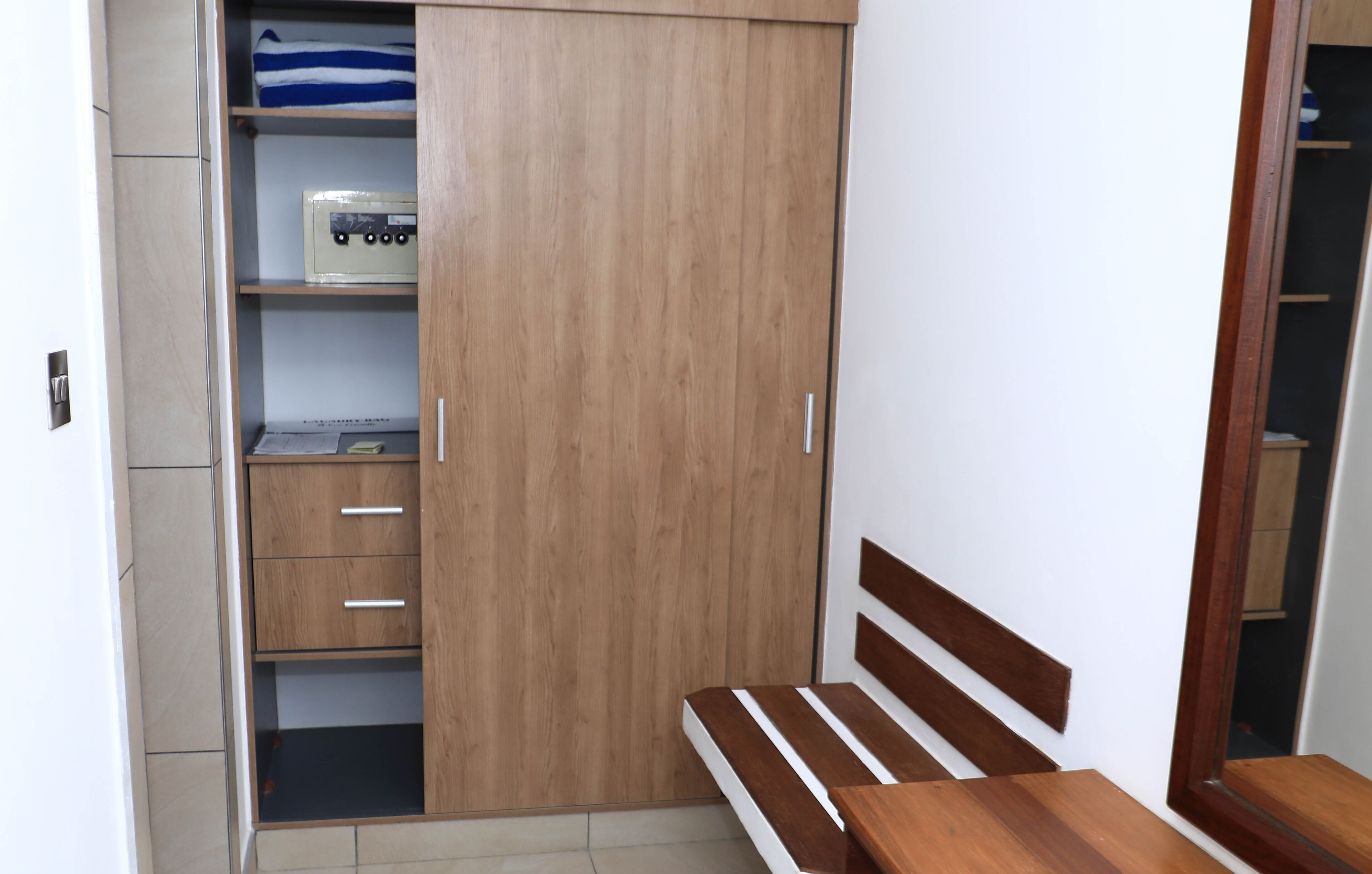 A bedroom with a wooden wardrobe, a bed with a wooden headboard, and a bedside table.