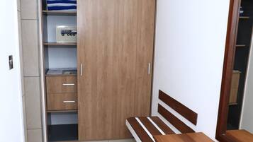A bedroom with a wooden wardrobe, a bed with a wooden headboard, and a bedside table.