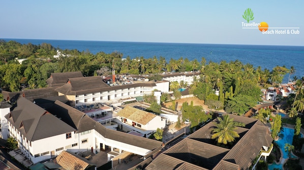 A resort with multiple buildings, a swimming pool, and a view of the ocean.