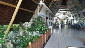 Un espacio interior amplio con suelo de baldosas, bancos de madera y una variedad de plantas.