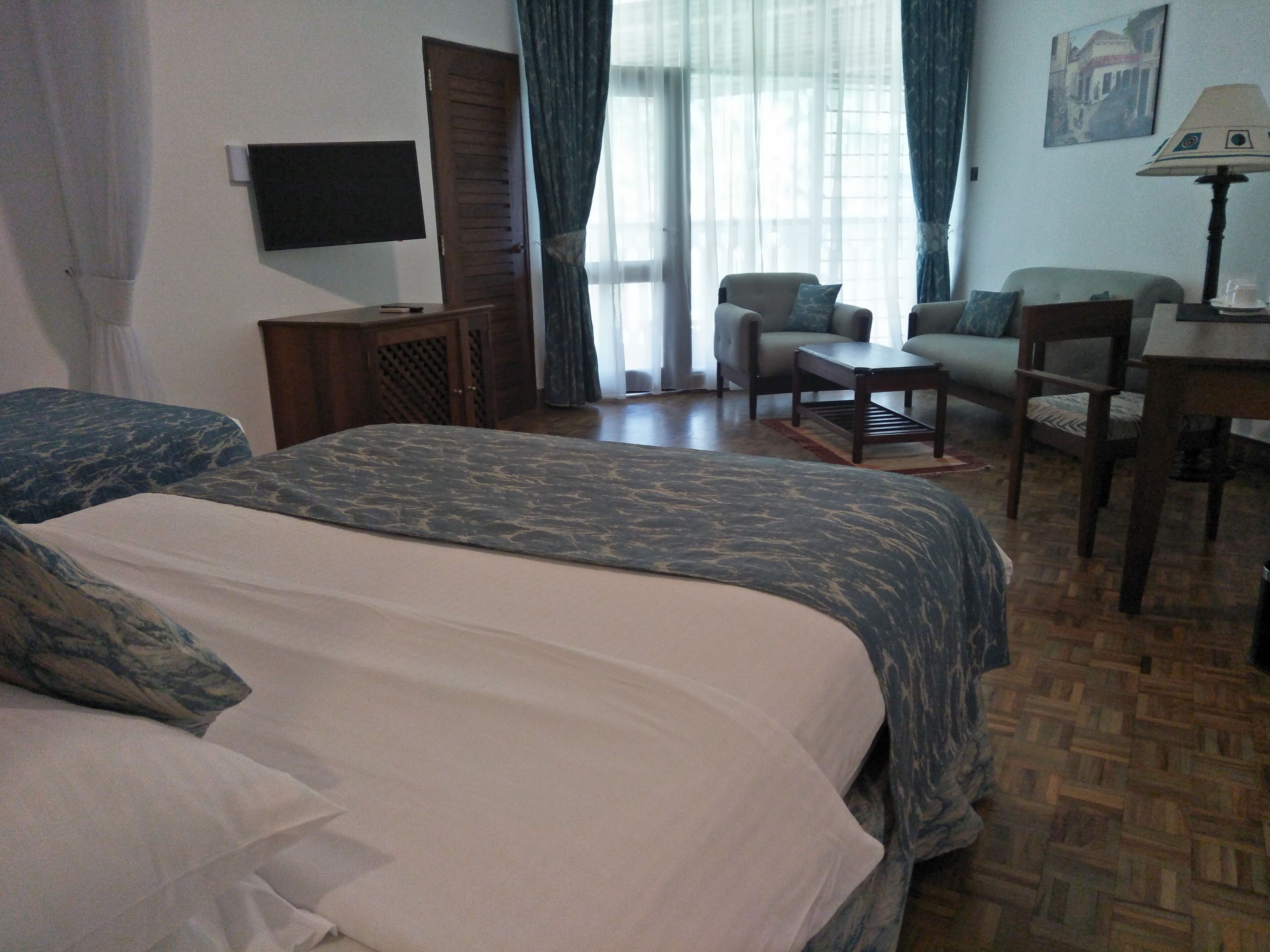A hotel room with two beds, a television, a desk with a lamp, and a chair.