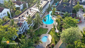 Vista aérea de un resort con varias edificaciones, piscina y exuberante follaje.