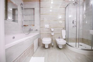 A modern bathroom with a bathtub, two toilets, a bidet, and a glass-enclosed shower. - Prestige Apart Hotel (Chisinau)