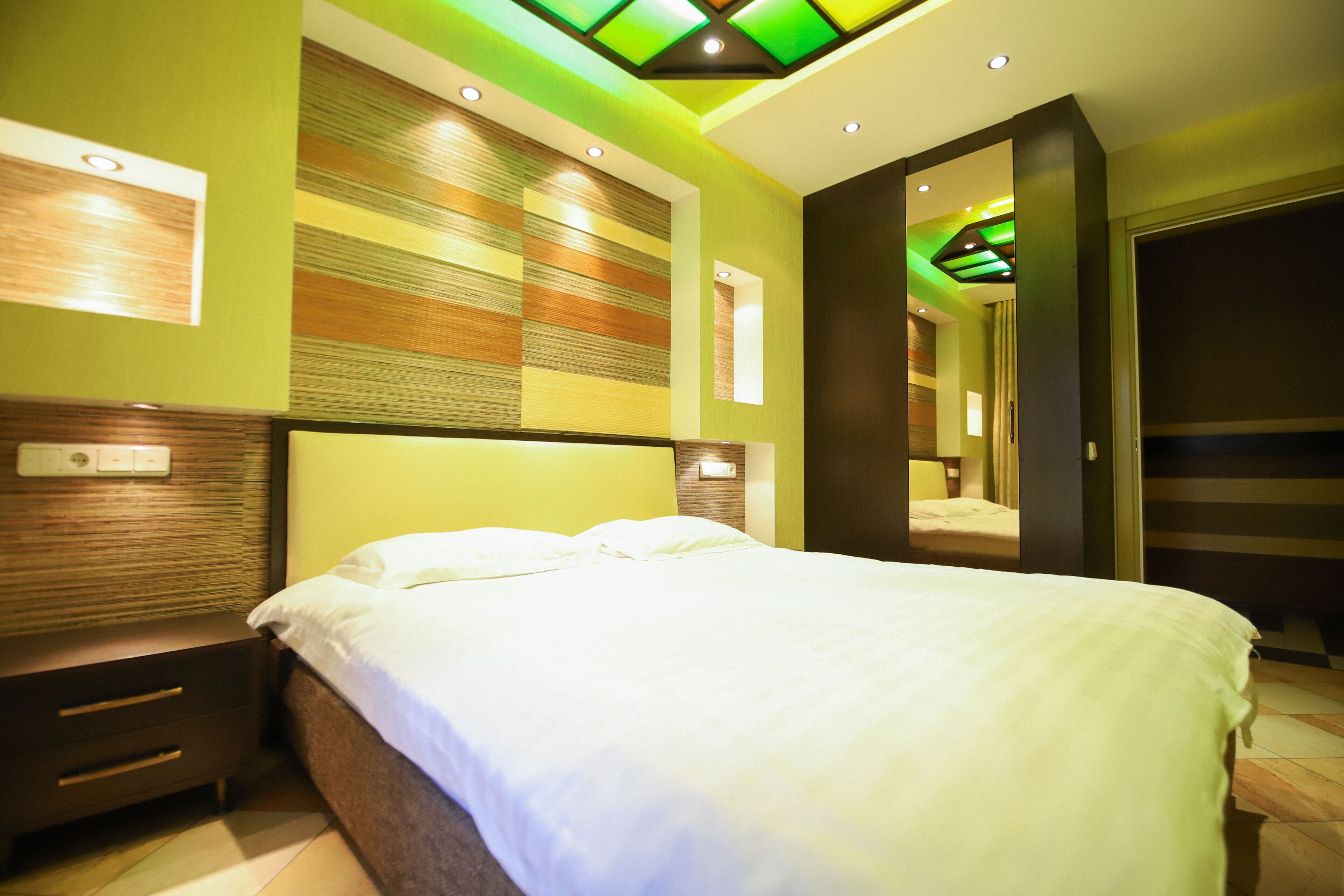 A modern hotel room with a large bed, a nightstand, and a mirror.