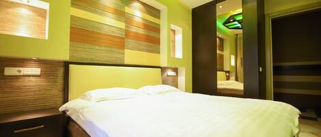 A modern hotel room with a large bed, a nightstand, and a mirror.